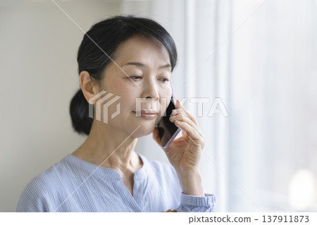 A woman in her late 50s talking on a smartphone A woman in her late 50s talking on a smartphone 137911873