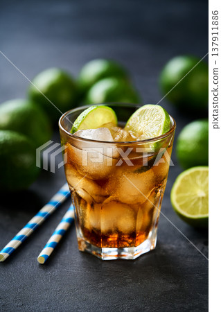 Cocktail cuba libre with brown rum, cola and lime in a glasses on a dark table. 137911886