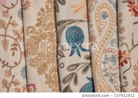 Close-up of colorful hand-woven fabrics with floral and pomegranate patterns, soft lighting Close-up of colorful hand-woven fabrics with floral and pomegranate patterns, soft lighting 137912912