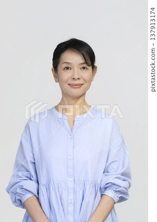 A woman in her late 50s smiling at the camera 137913174