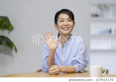 A woman in her late 50s waving at the camera A woman in her late 50s waving at the camera 137913179