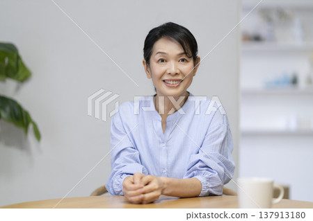 一位年近六十的女士對著鏡頭微笑 一位年近六十的女士對著鏡頭微笑 137913180