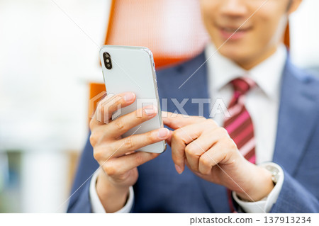 A businessman operating a smartphone A businessman operating a smartphone 137913234