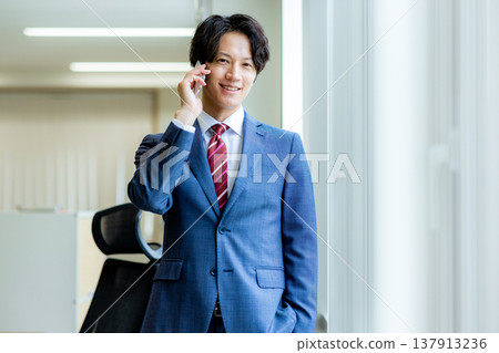 A young businessman making a phone call on his smartphone in the office. 137913236