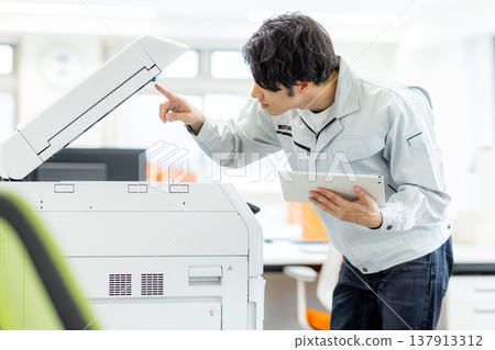 A man inspecting a copier A man inspecting a copier 137913312