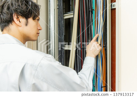 A man operating a switchboard in a factory 137913317