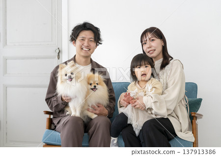 笑容燦爛的年輕家庭和他們的兩隻寵物狗正看著鏡頭。 笑容燦爛的年輕家庭和他們的兩隻寵物狗正看著鏡頭。 137913386