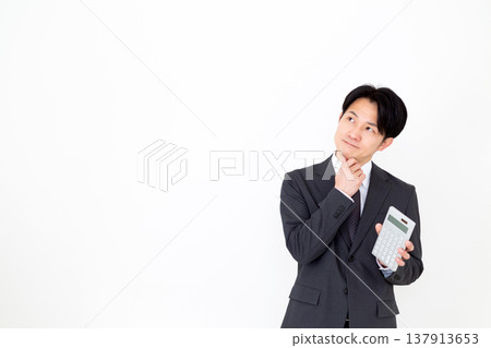 一位穿著西裝的中年男性商人拿著計算器,憂心忡忡 一位穿著西裝的中年男性商人拿著計算器,憂心忡忡 137913653
