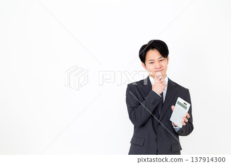 A middle-aged male businessman in a suit holding a calculator and worrying A middle-aged male businessman in a suit holding a calculator and worrying 137914300