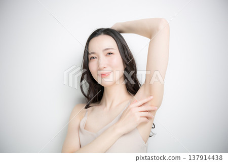 Image of a young woman receiving beauty treatments and esthetic services for her upper body, such as underarms and arms, against a white background. 137914438