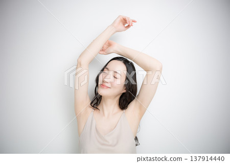 一位年輕女子在白色背景下接受上半身（如腋下和手臂）美容護理和美學服務的圖片。 137914440