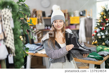 Young woman choosing platform boots on Christmas tree background Young woman choosing platform boots on Christmas tree background 137914654