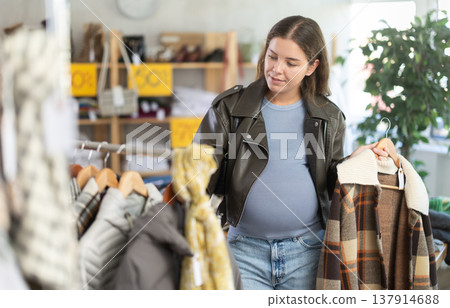 Pregnant woman chooses plaid jacket in clothing store Pregnant woman chooses plaid jacket in clothing store 137914688
