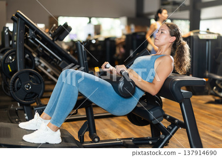 Sportive young girl training on hip thrust machine in gym Sportive young girl training on hip thrust machine in gym 137914690