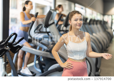 Woman standing on the background of exercise equipment Woman standing on the background of exercise equipment 137914700