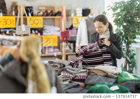 Attentive middle-aged woman choosing sweater in clothing store Attentive middle-aged woman choosing sweater in clothing store 137914737