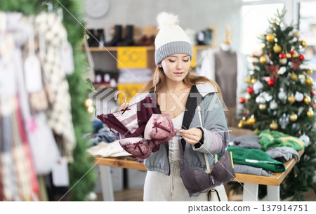 Girl client looks at products in store, looks closely at bra, picks up wardrobe item 137914751
