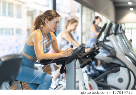Woman exercising on an exercise bike in the gym Woman exercising on an exercise bike in the gym 137914753