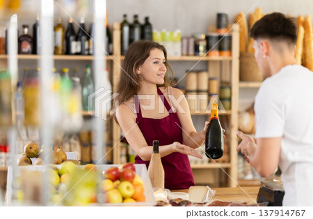 Young woman seller offers wine to man Young woman seller offers wine to man 137914767