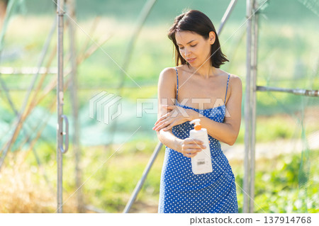 Adult woman applying sunscreen in garden greenhouse 137914768