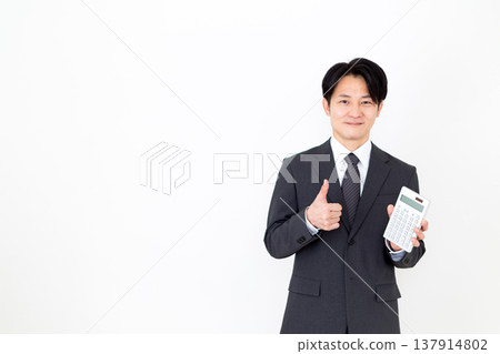 A middle-aged male businessman in a suit holding a calculator and making a fist pump A middle-aged male businessman in a suit holding a calculator and making a fist pump 137914802
