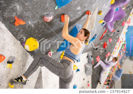 Woman training at bouldering gym without special climbing equipment Woman training at bouldering gym without special climbing equipment 137914827