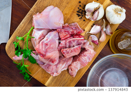 Raw sliced rabbit lying on wooden cutting board with seasonings Raw sliced rabbit lying on wooden cutting board with seasonings 137914843