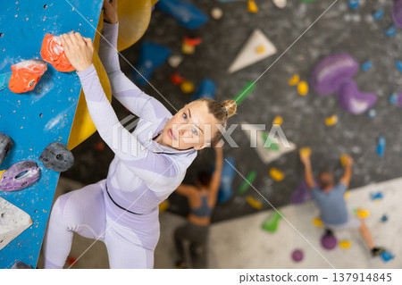Adult woman practicing rock climbing on climbing wall Adult woman practicing rock climbing on climbing wall 137914845