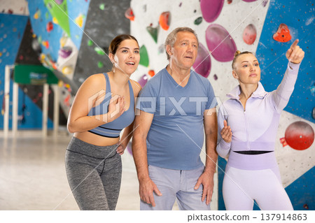 Sports women and man are actively discussing the successes and mistakes of other athletes on mountaineering simulator Sports women and man are actively discussing the successes and mistakes of other athletes on mountaineering simulator 137914863