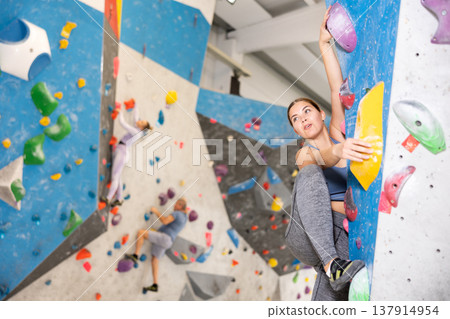 Focused sporty young girl climbing on bouldering wall 137914954