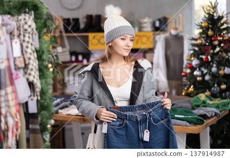 Woman in a knitted hat choosing jeans in a store 137914987