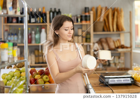 Female shopper chooses which cheese to buy at supermarket Female shopper chooses which cheese to buy at supermarket 137915028