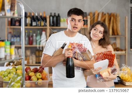 Young couple following shopping list to buy snacks in grocery store Young couple following shopping list to buy snacks in grocery store 137915067