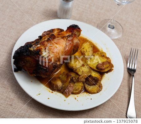 Portion of pork knuckle with boiled potatoes and gravy in plate 137915078