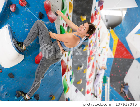 Young woman practicing rock climbing on climbing wall Young woman practicing rock climbing on climbing wall 137915089