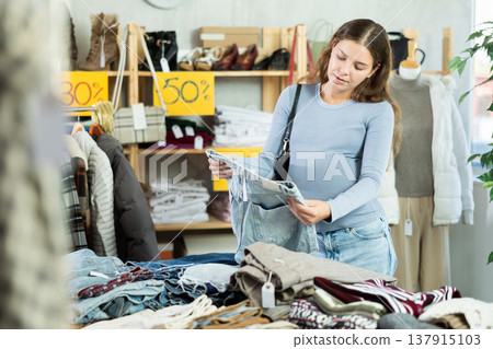 Selective pregnant woman choosing jean pantaloons in clothing store 137915103