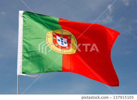 Beautiful large red and green Portuguese flag waving in wind against blue sky. 137915105