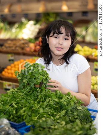 Young asian girl hoosing fresh greens in farm store 137915106