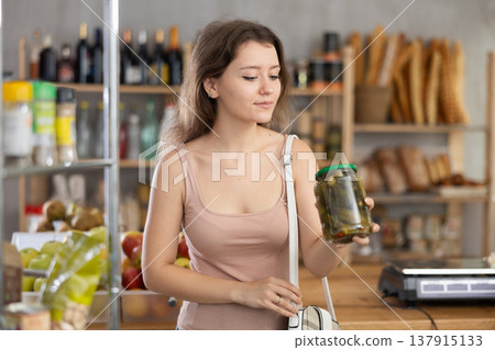 Thoughtful young woman choosing pickles in grocery store 137915133