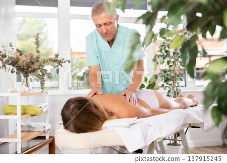 male masseur giving massage to female patient male masseur giving massage to female patient 137915245