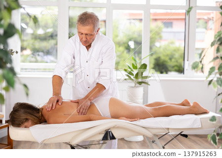 male masseur giving massage to female patient male masseur giving massage to female patient 137915263