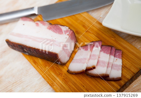 Closeup of traditional sliced smoked lard with parsley on cutting board 137915269