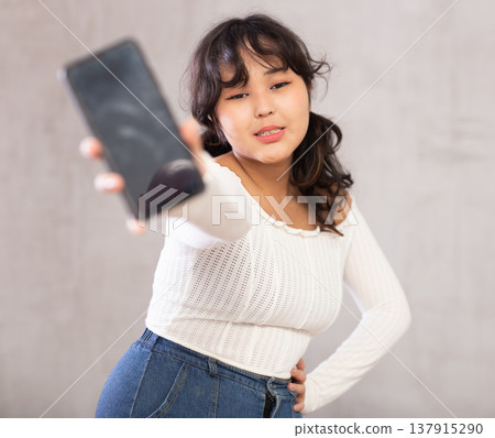 Displeased young girl holding mobile phone Displeased young girl holding mobile phone 137915290