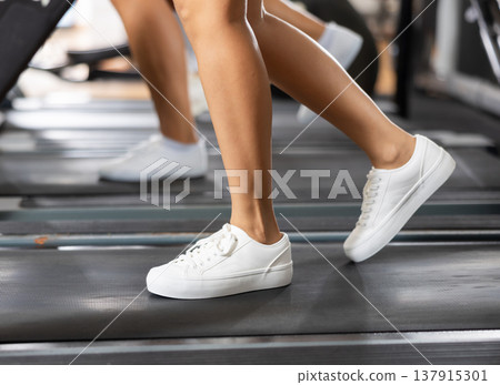 Feet of young girl walk on treadmill in gym Feet of young girl walk on treadmill in gym 137915301