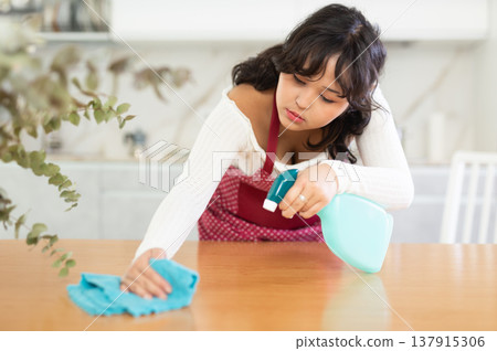 Housewife cleaning table surface with rag in modern kitchen Housewife cleaning table surface with rag in modern kitchen 137915306