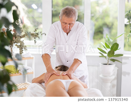 male masseur giving massage to female patient male masseur giving massage to female patient 137915340