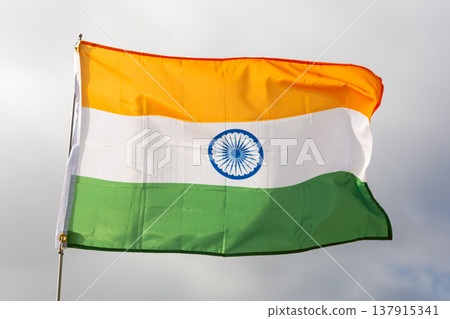 Against background of cloudy sky, tricolour Indian flag flutters on flagpole Against background of cloudy sky, tricolour Indian flag flutters on flagpole 137915341