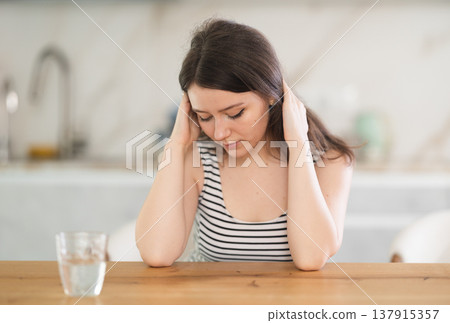 Thoughtful young woman sitting at table Thoughtful young woman sitting at table 137915357