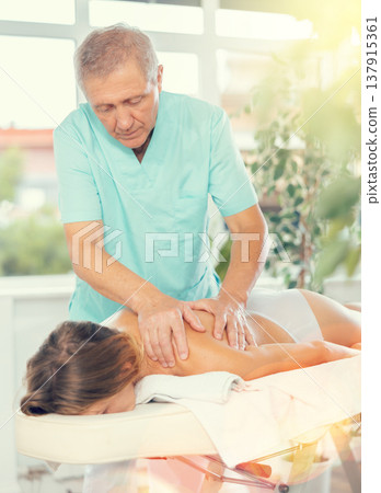 male masseur giving massage to female patient 137915361