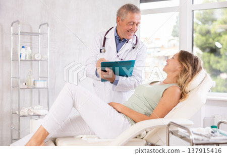 Male doctor carries out questionnaire survey of woman after procedure 137915416